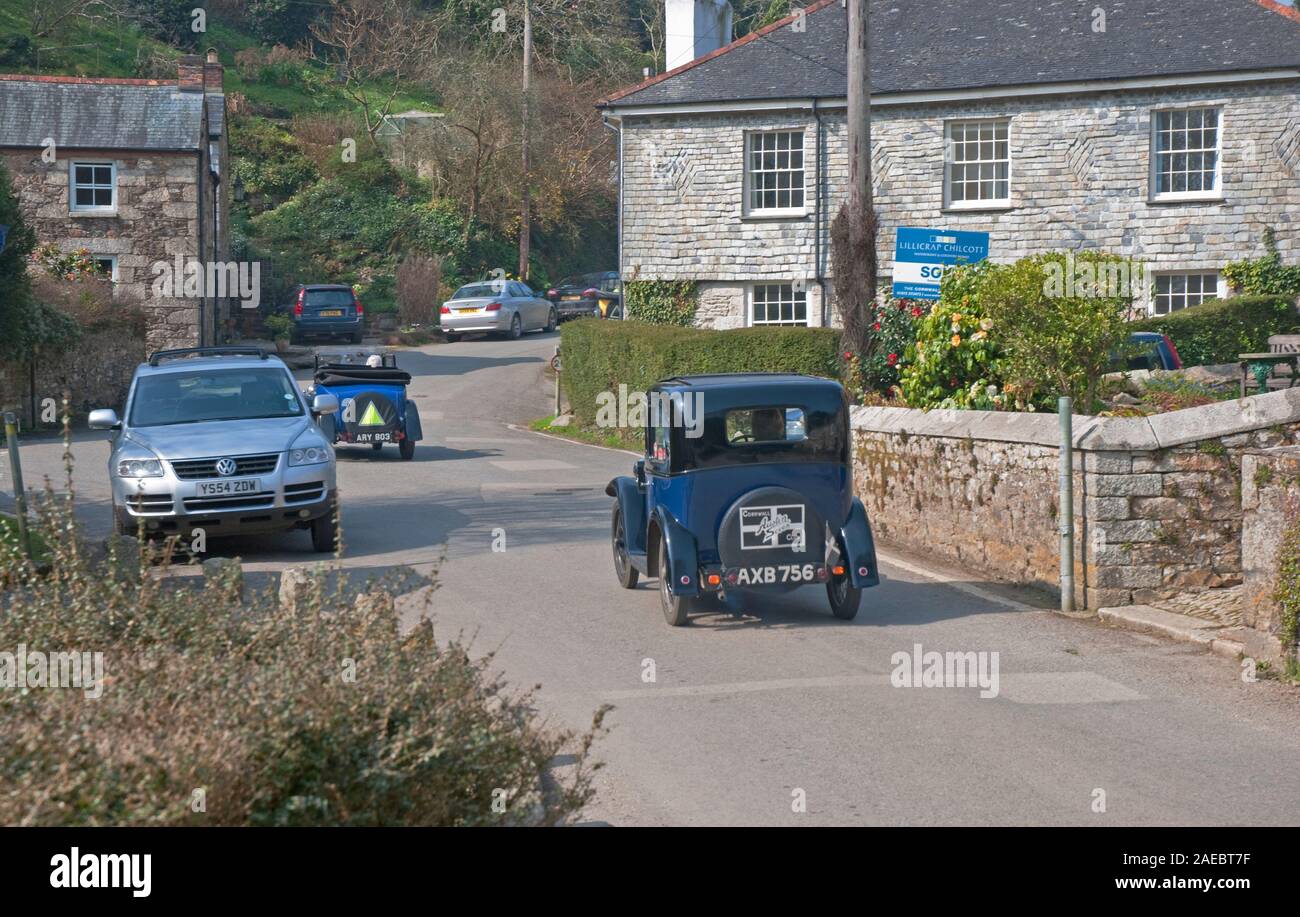 Two small veteran cars driving through the small village of Port Navas near Falmouth, south Cornwall, south west England, UK Stock Photo
