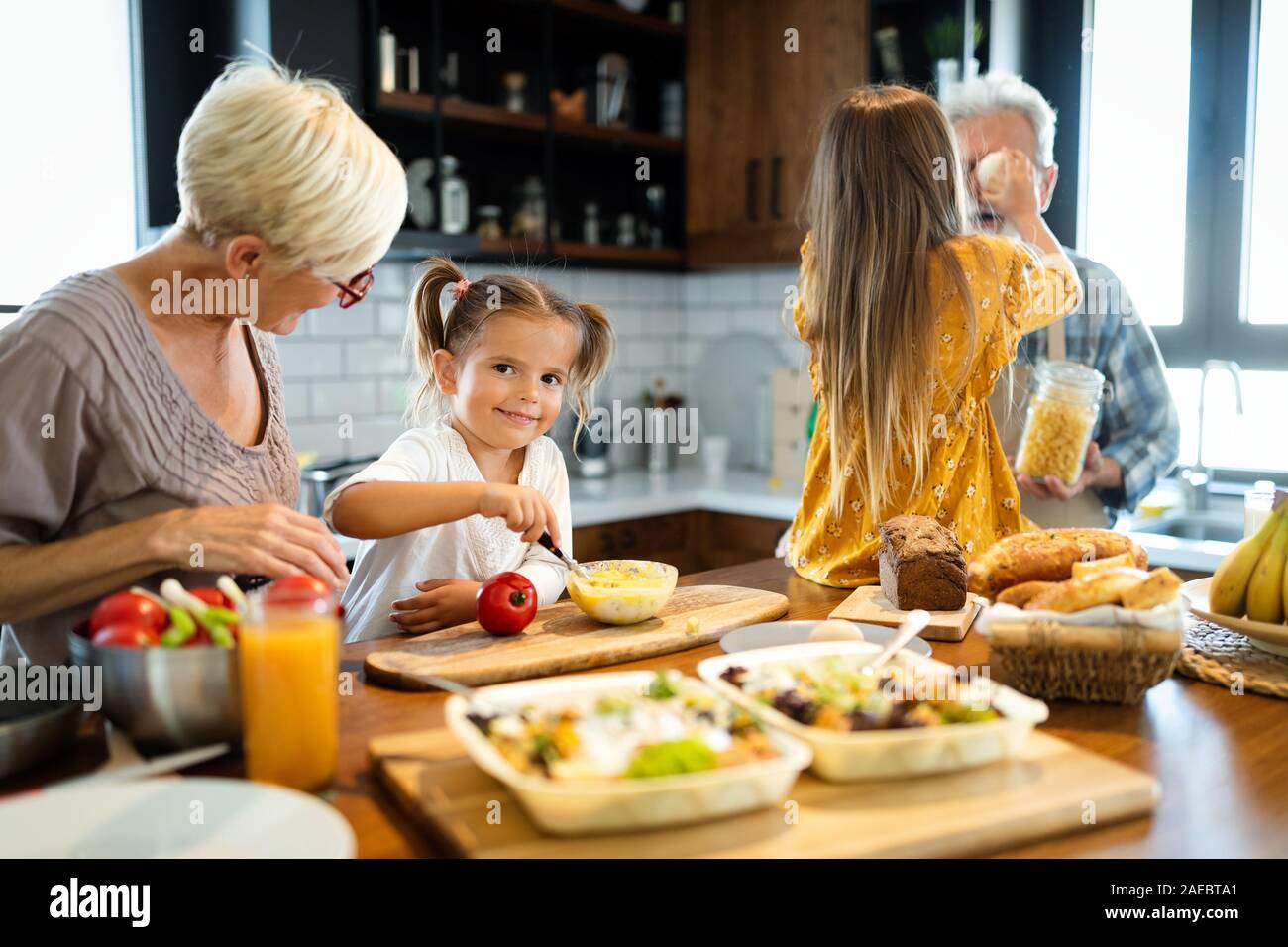 Happy grandparents with grandchildren making breakfast in kitchen Stock ...