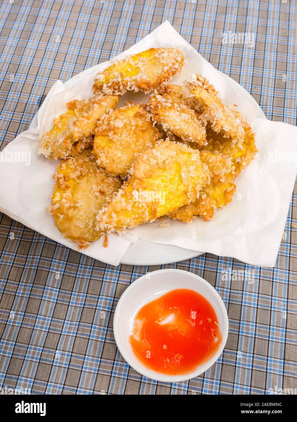 Deep fried sweet potato fritters covered in coconut served on table