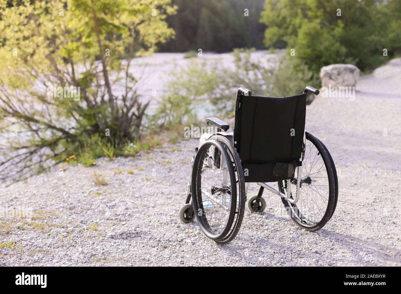 Empty wheelchair standing in a park on walking path Stock Photo