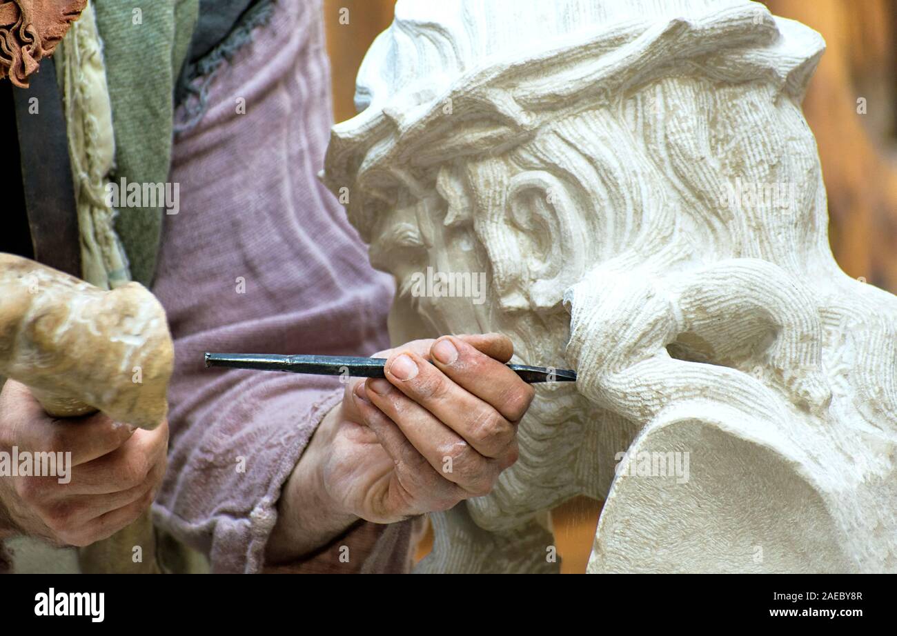 Sculptor stone carving a Christ with the crown of thorns. Professional craftsman, an artist working manually. Stock Photo