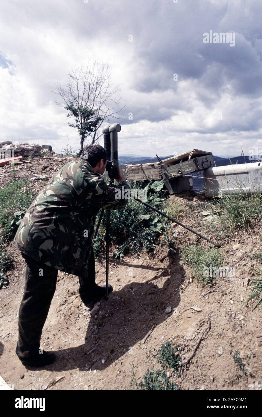 11th August 1993 During the Siege of Sarajevo: a Bosnian-Serb soldier uses WW2 trench binoculars to view the city below, next to his bunker on Mount Trebevic. Stock Photo