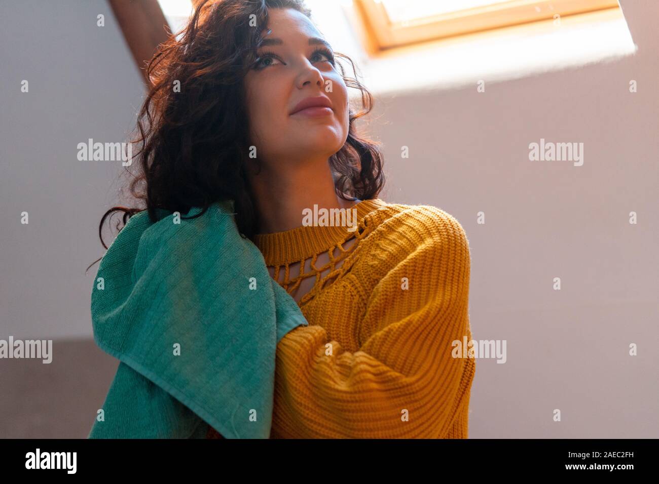 Young attractive woman in yellow sweater drying curly hair