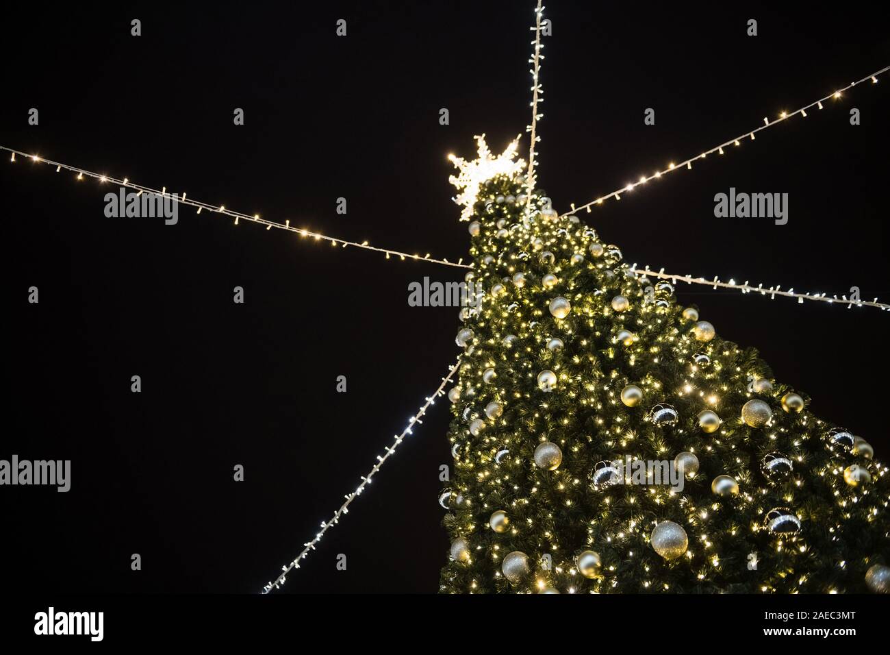 Stylish Christmas tree with golden lights and illuminated star on top ...