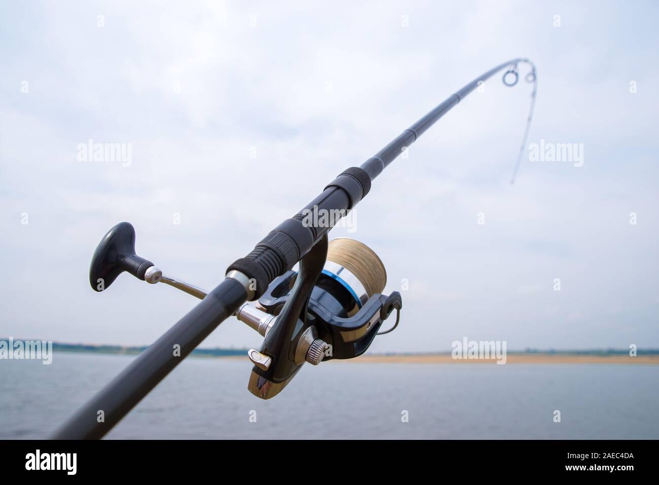 Fishing rod with reel close-up. The fishing rod is bent and fully
