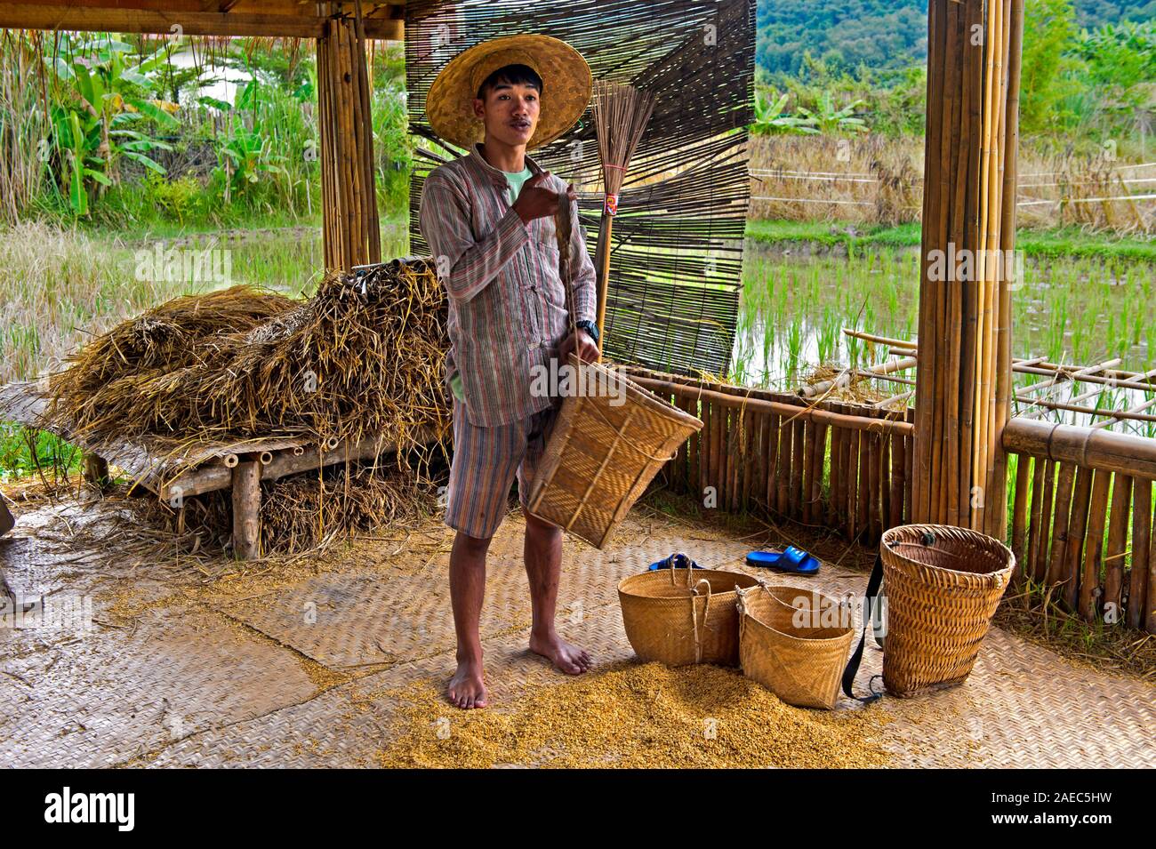 Young manshowing baskets for storage and transportation of rice, demonstration of traditional rice producing technology, Luang Prabang, Laos Stock Photo