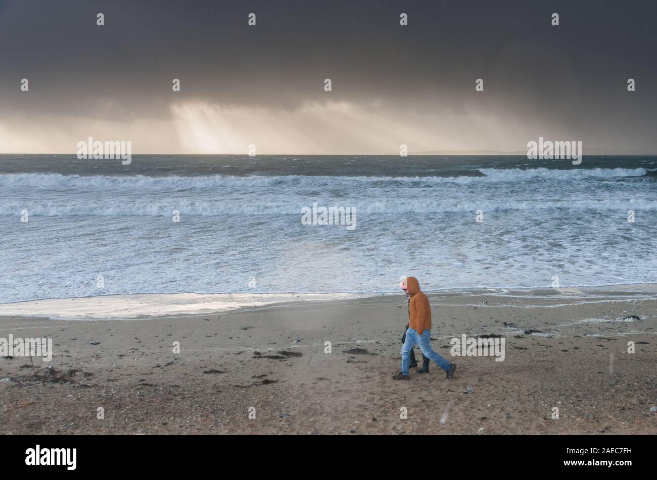 Garrettstown, Cork, Ireland. 08th December, 2019. With a status Red alert in operation due to the arrival of Storm Atiyah, a young couple walk on the beach as dark brooding skies approach the coast at Garrettstown, Co. Cork, Ireland. - Credit; David Creedon / Alamy Live News Stock Photo