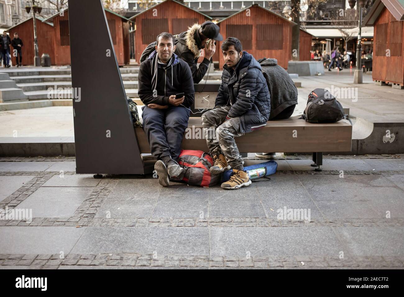 Serbia, Nov 26, 2019: A small group of migrants from the Middle East charging their cell phones at the Republic Square in Belgrade city center Stock Photo