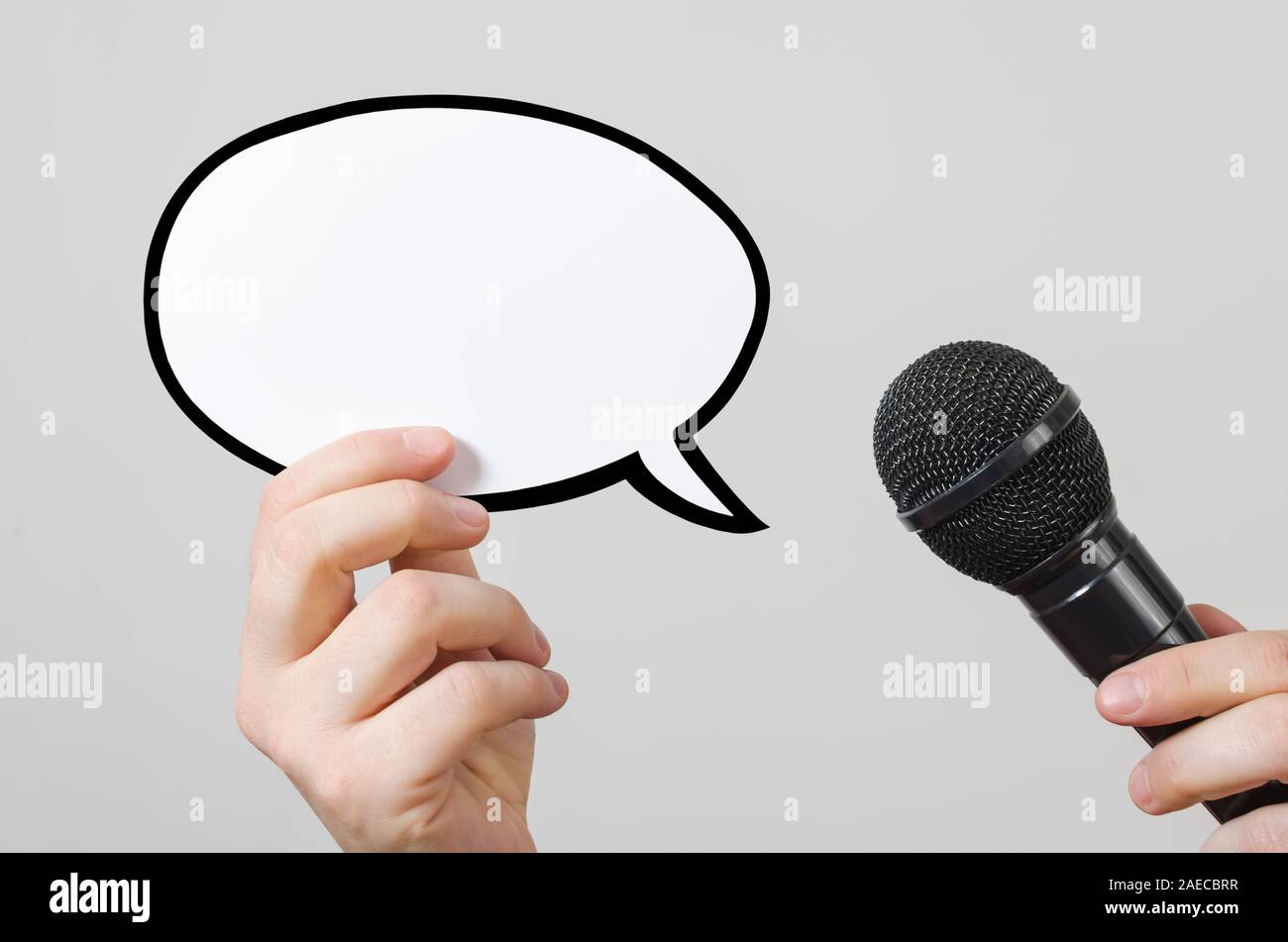 Hands holding a blank speech bubble and microphone. Conference, interview or social media concept with microphone and blank speech bubbles Stock Photo