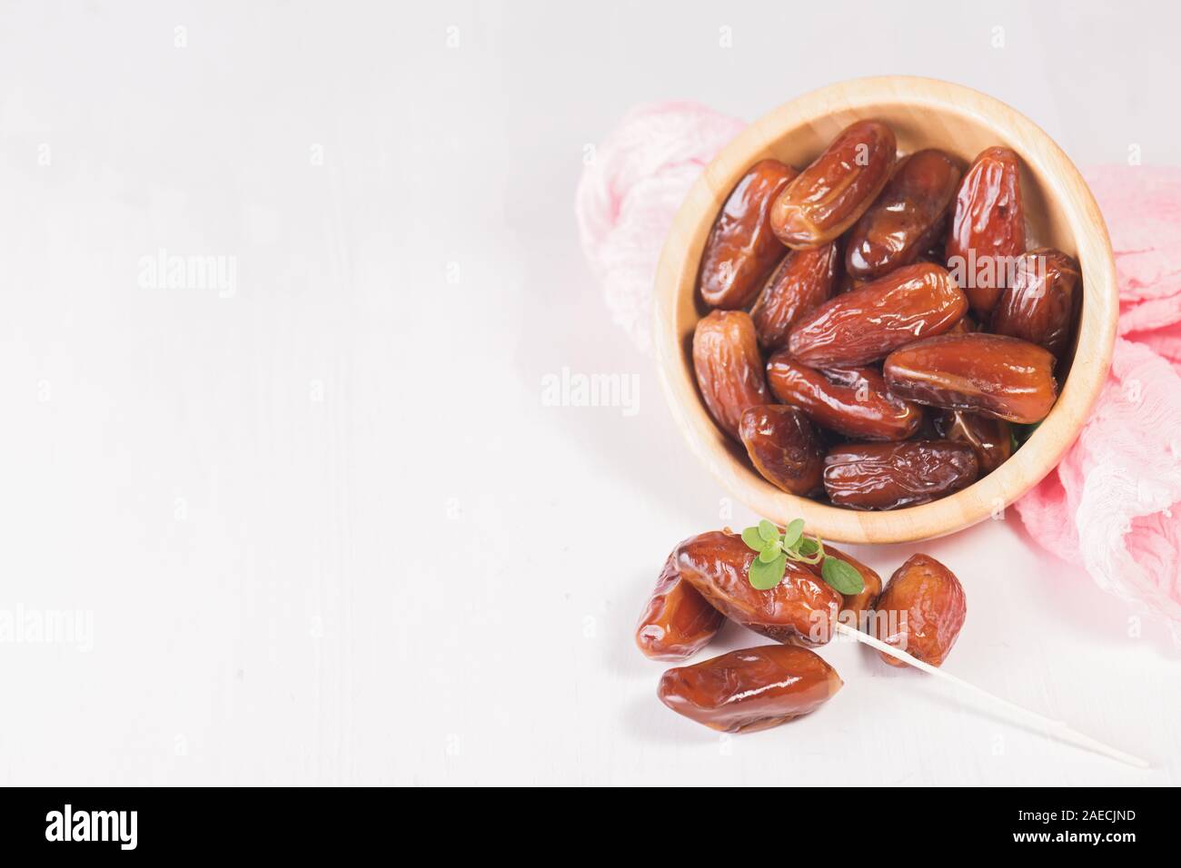 Raw sweet dry dates with in a terracotta bowl on a white background