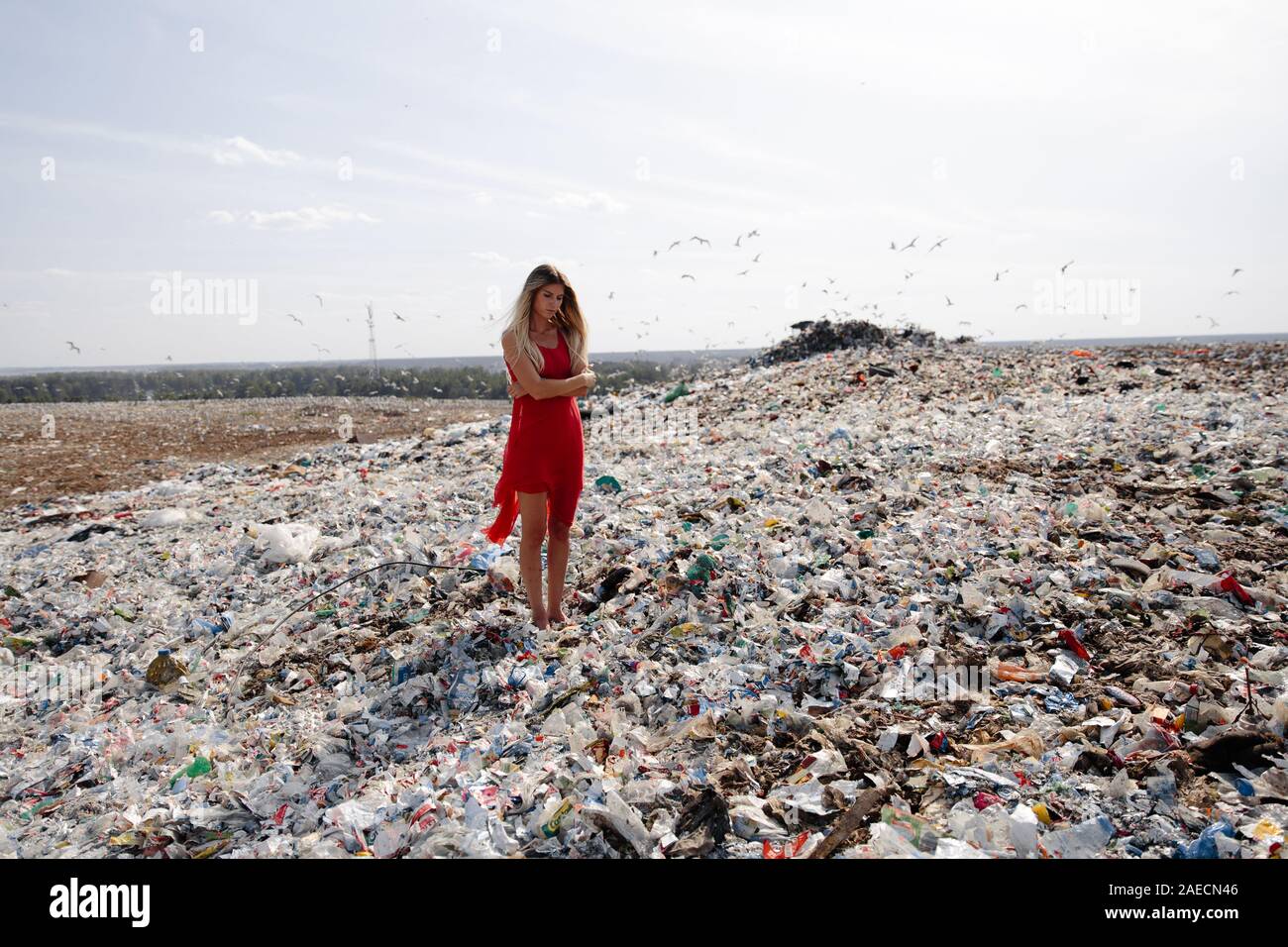 Nature pollution activist at a huge trash dump outdoors - Young blonde ...