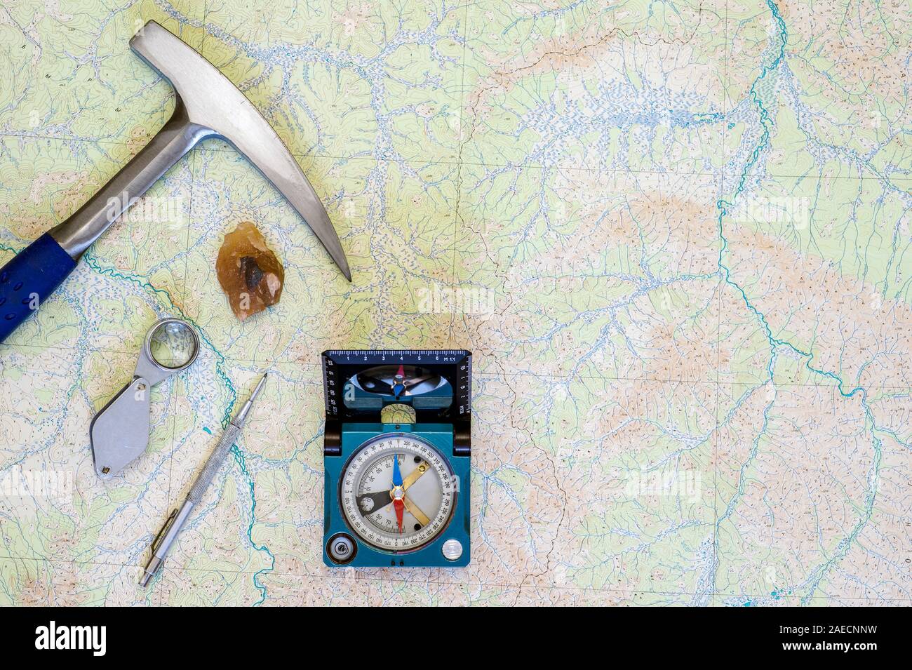 The tools of the geologist laid out on a topographic map. Background