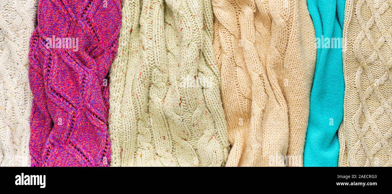 Several Different Colorful Knitted Sweaters Lays Side by Side as Background Stock Photo