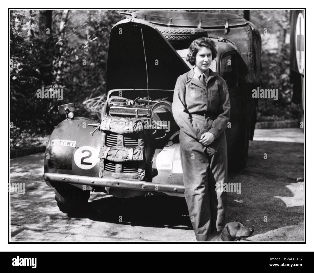 Vintage 1940's Princess Elizabeth (later to be Queen Elizabeth II) stands shyly posing for a photo showing her determination to be a part of the ATS (Auxiliary Territorial Service) training on the repair and maintenance of British World War II military vehicles Princess Elizabeth trained as a driver and mechanic and was given the rank of honorary junior commander Stock Photo