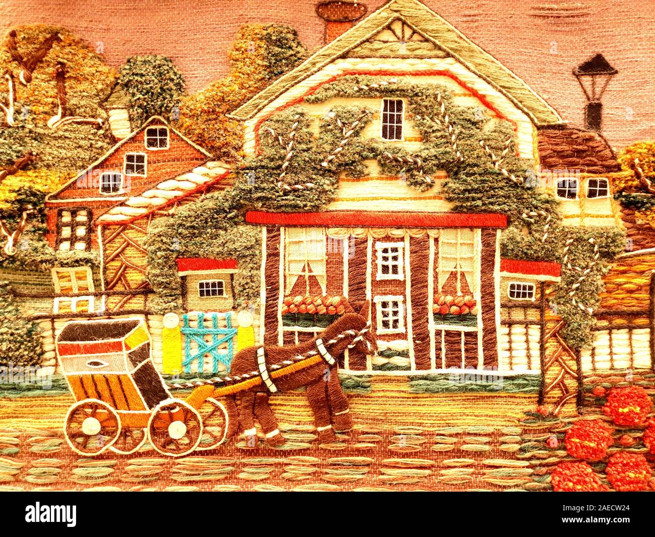Beautiful embroidery with a countryside scene. A horse cart is passing by at home. Stock Photo