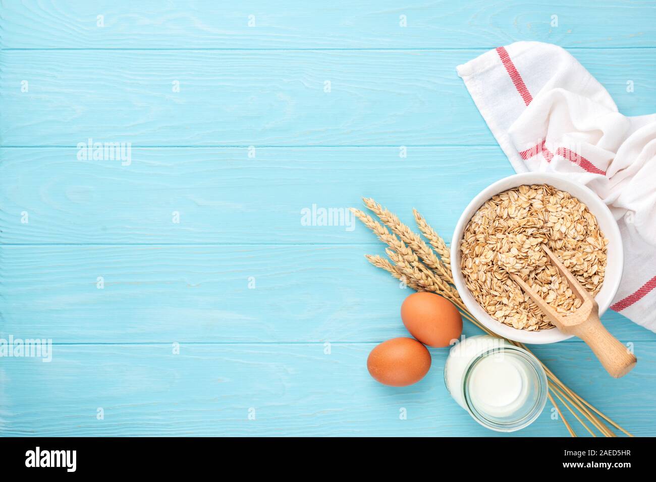 Rolled oats, bottle of milk and eggs - healthy breakfast food concept. On blue wooden table background. Copy space for text Stock Photo
