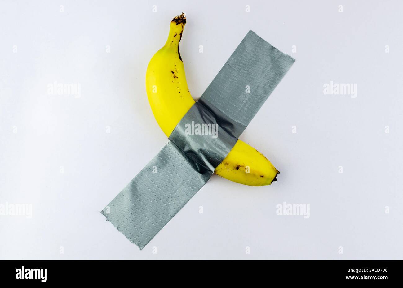 Banana duct taped to the white wall. Conceptual photo. Stock Photo