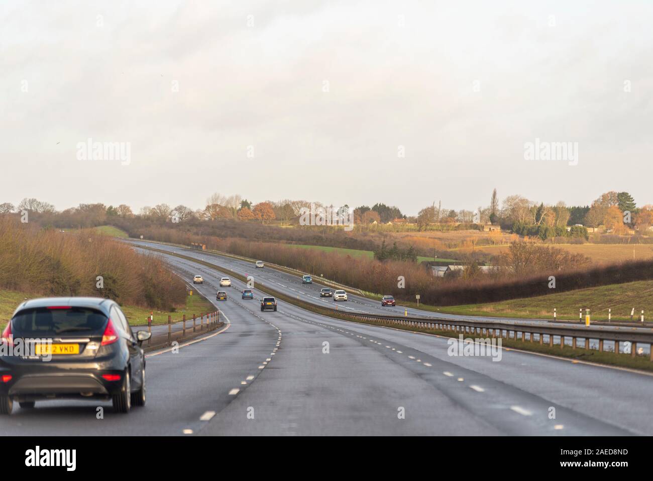 Vehicles driving on a stretch of A130 three lane carriageway with Rettendon on horizon with dip in the road near Runwell, Essex, UK. Damp winter drive Stock Photo