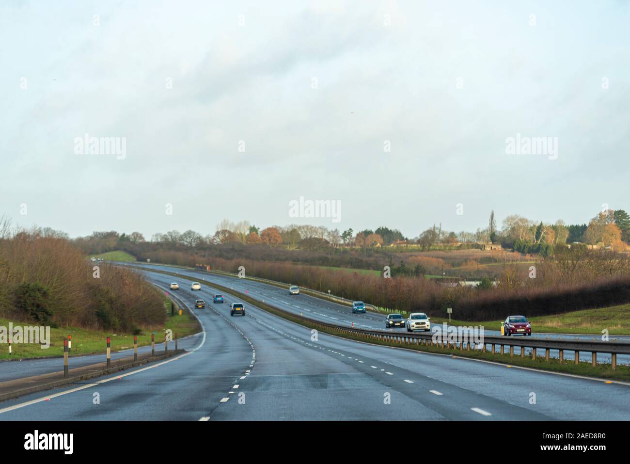 Vehicles driving on a stretch of A130 three lane carriageway with Rettendon on horizon with dip in the road near Runwell, Essex, UK. Damp winter drive Stock Photo