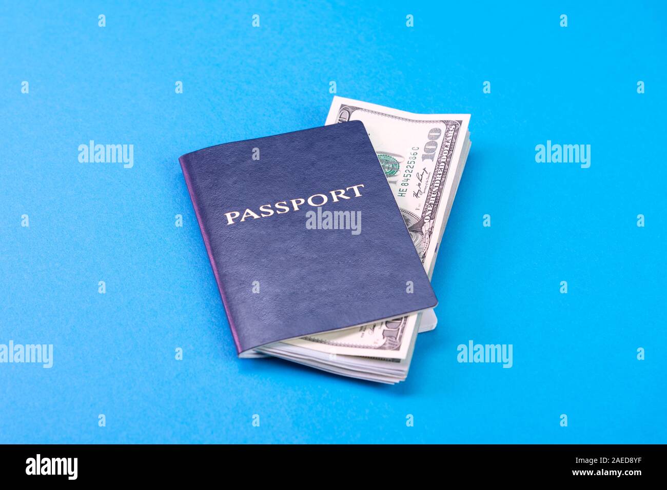 Blue passport with american dollars in 100 bills on a blue background