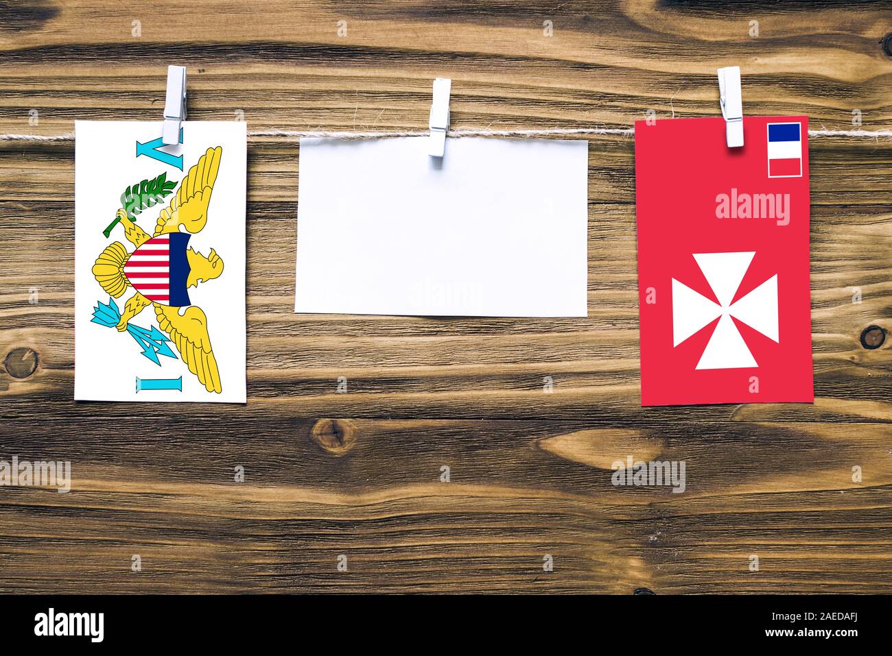 Hanging flags of United States Virgin Islands and Wallis And Futuna attached to rope with clothes pins with copy space on white note paper on wooden b Stock Photo