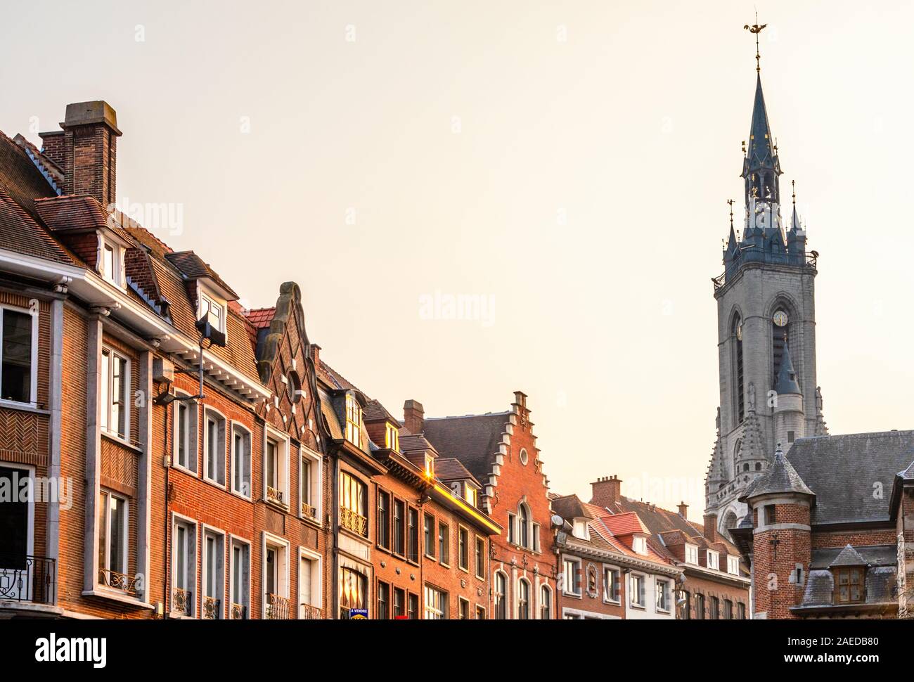 Tall medieval bell tower rising over the street with old european houses, Tournai, Walloon municipality, Belgium Stock Photo