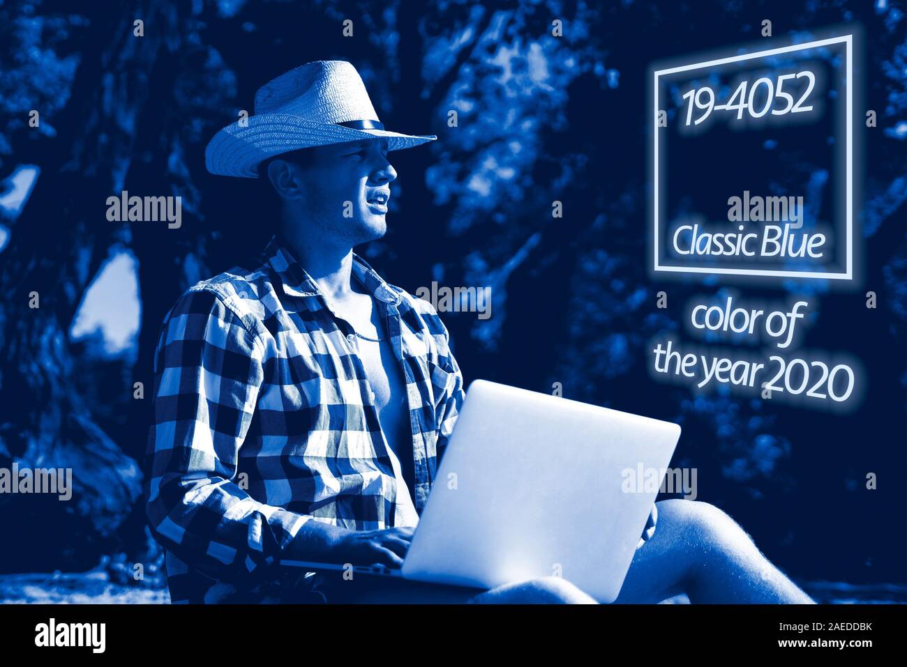 young handsome attractive man sitting on the sandy tropical exotic beach on a summer resort working on a laptop Stock Photo