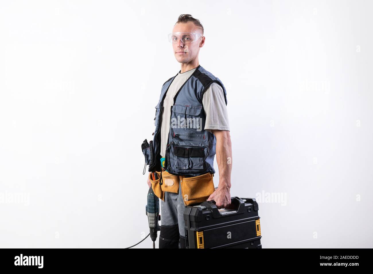 Builder with tools in cases. In a helmet and glasses, and unloading. Stock Photo
