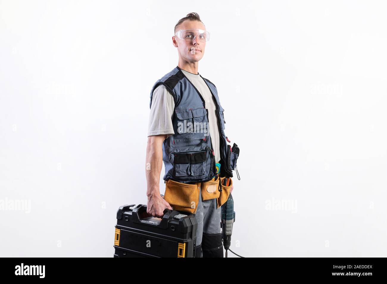 Builder with tools in cases. In a helmet and glasses, and unloading. Stock Photo