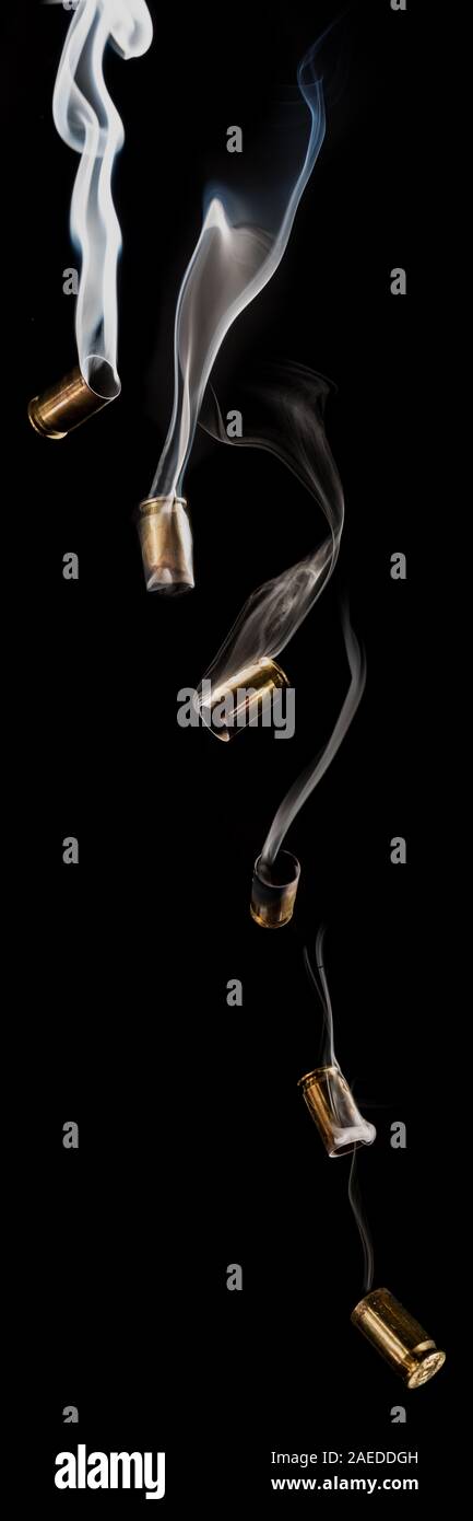 Bullet casings fall through the air, smoking as though they've just been fired. Stock Photo