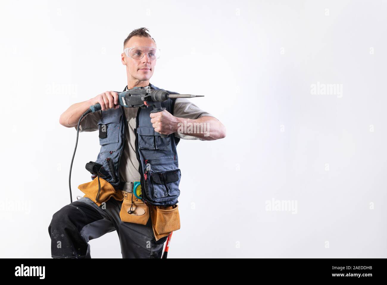 Builder with a drill in his hands, in unloading, aims to the right. Stock Photo