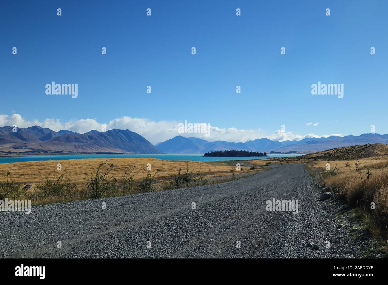 Empty road with a blue lake and mountains in the background Stock Photo