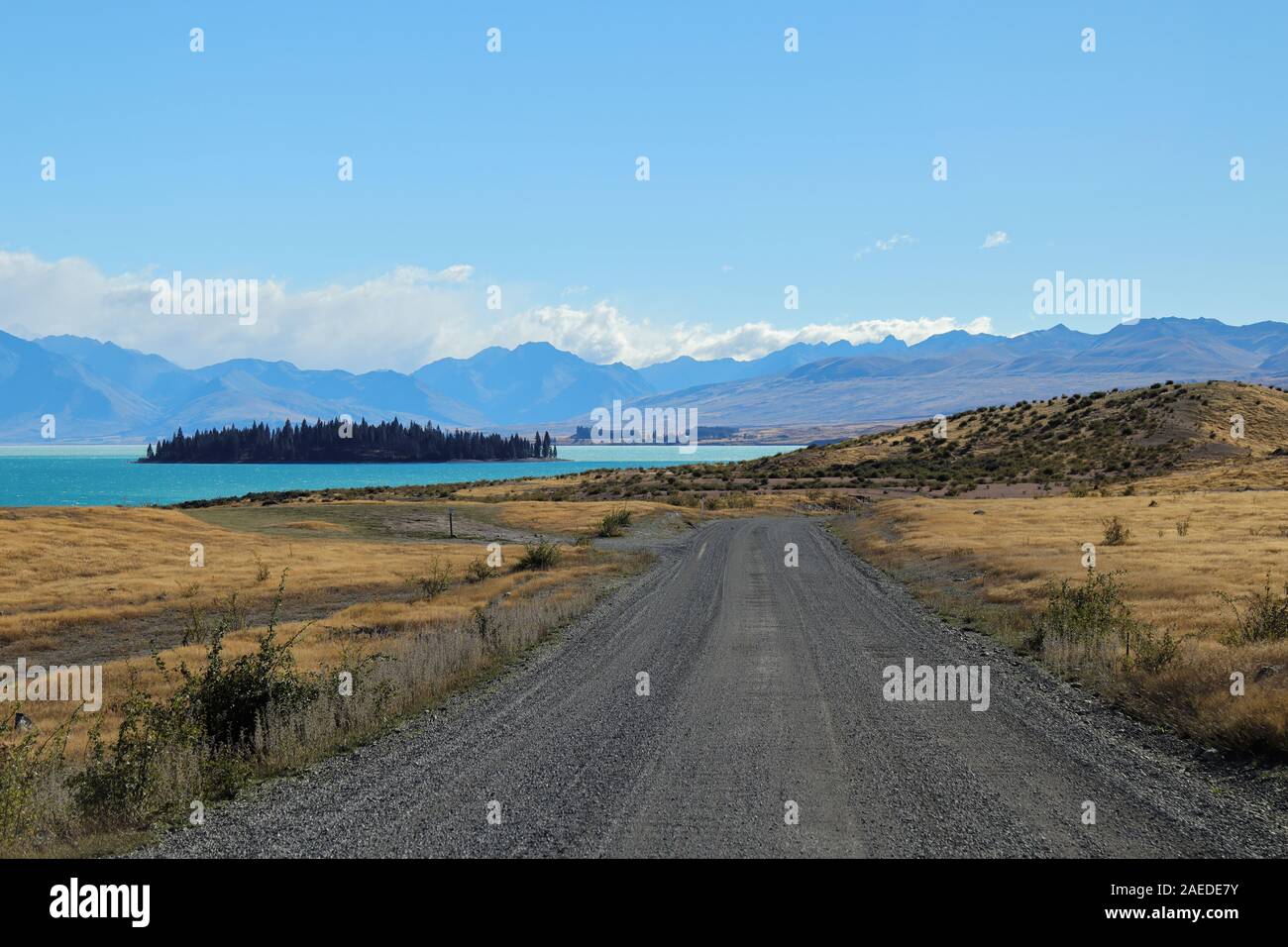 Empty road with a blue lake and mountains in the background Stock Photo