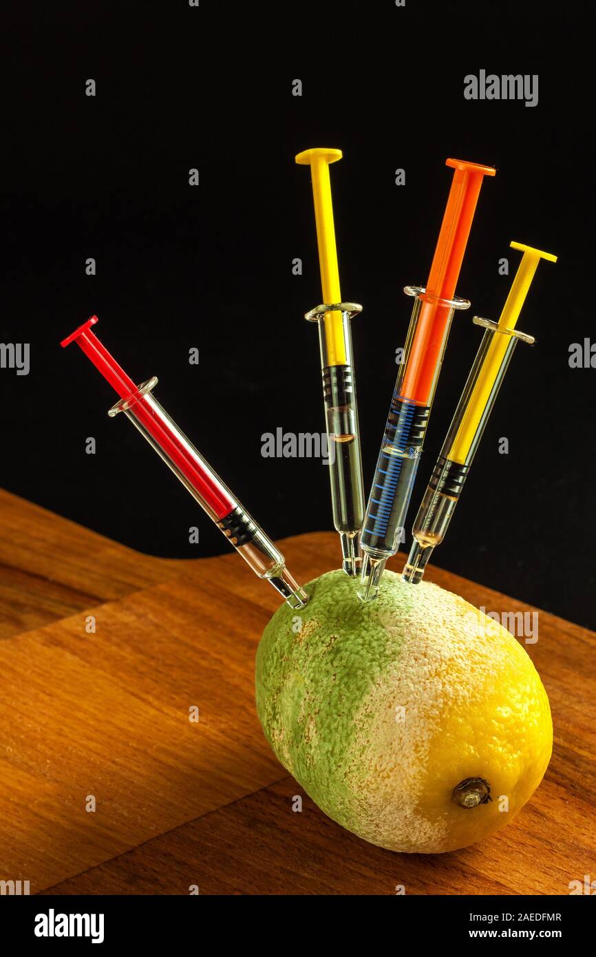 Moldy lemon with syringe. Chemistry in food. Unhealthy food. Decayed ...