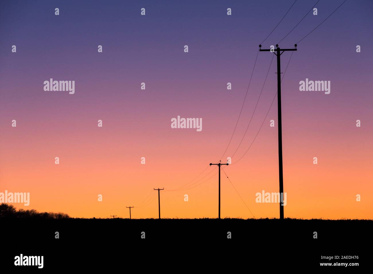 National Grid electricity power lines cross the Suffolk countryside after the winter's sun has set. Stock Photo