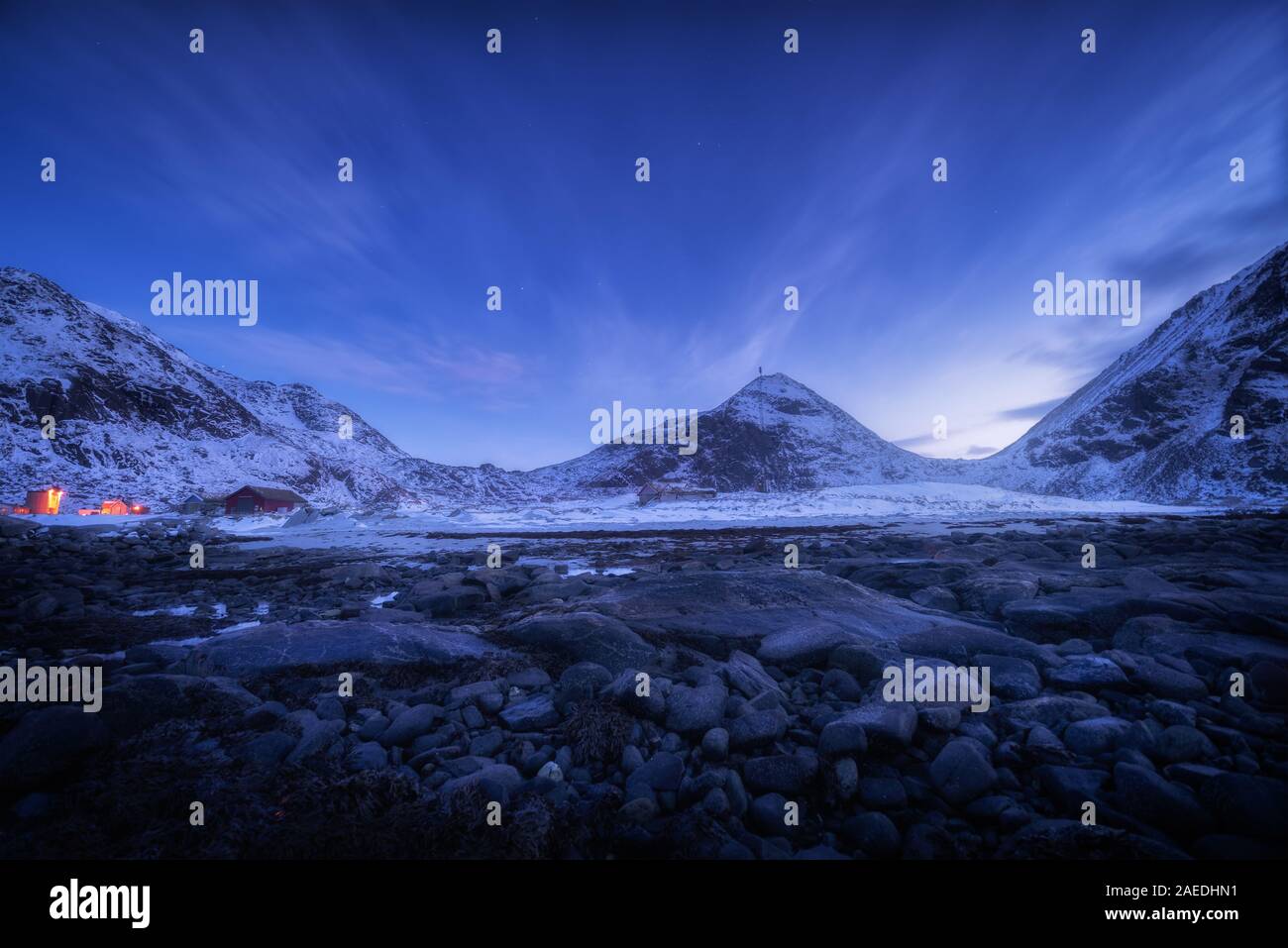 Blue sky with stars rocky beach and snow covered mountains Stock Photo