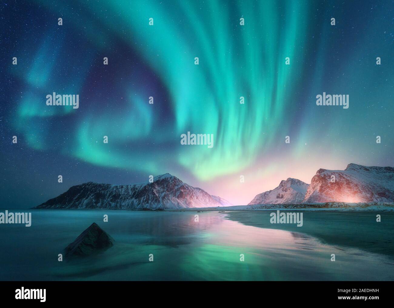 Aurora borealis over the sea and snowy mountains. Northern lights Stock Photo