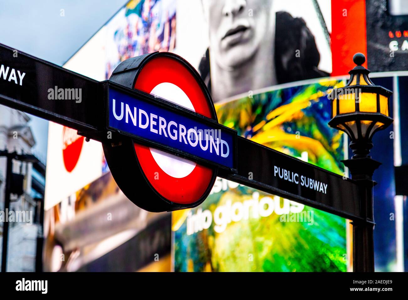 Underground tube entrance sign with the advertising screen in the background at Piccadilly Circus, London, UK Stock Photo