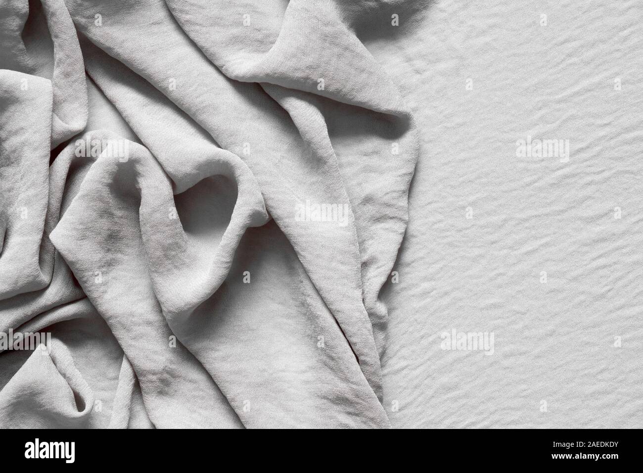 Folds of natural gray beige fabric, top view, background or concept. Stock Photo