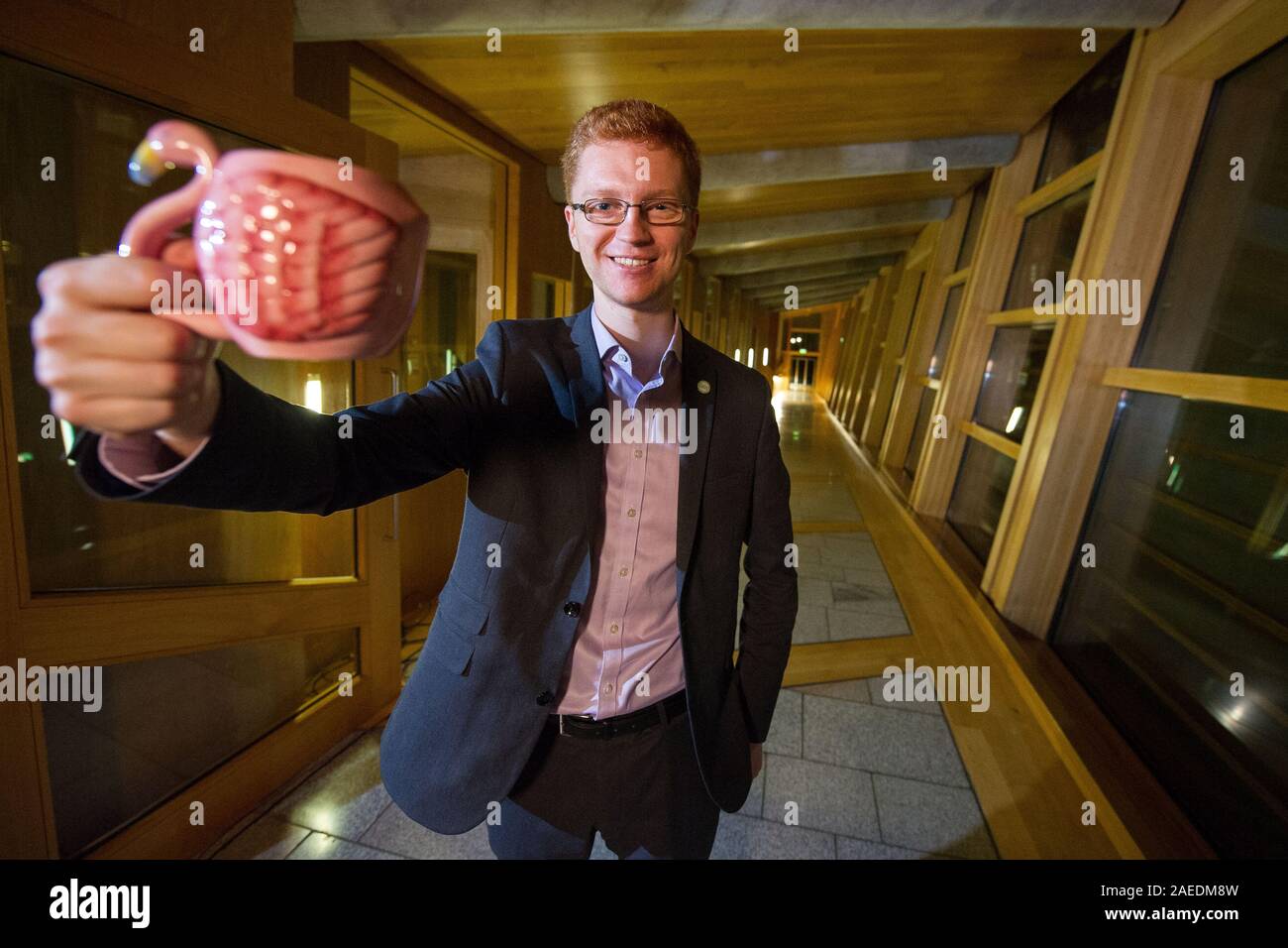 Edinburgh, UK. 7 November 2019. Pictured: Ross Greer MSP, Scottish green Party., holding a flamingo shaped mug of tea. The Scottish Green Party have halted the proposed development of Flamingo Land at Loch Lomond. Credit: Colin Fisher/Alamy Live news. Stock Photo