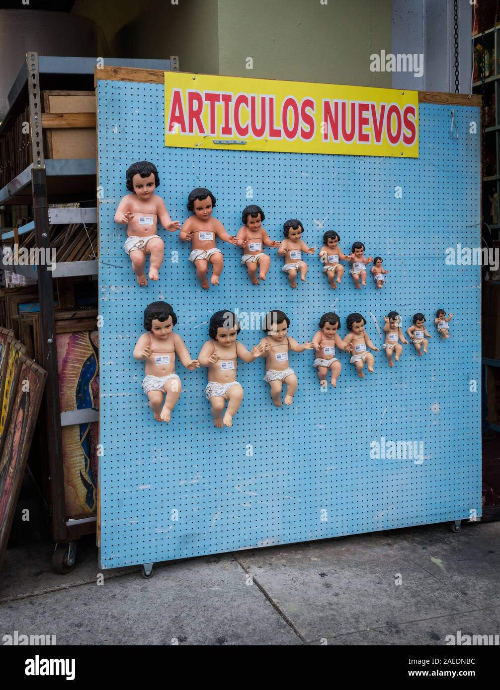 Rows of baby Jesus figures on display at a store in Downtown Los Angeles, California, below sign, in Spanish, reading: "Articulos Nuevos" (new items). Stock Photo