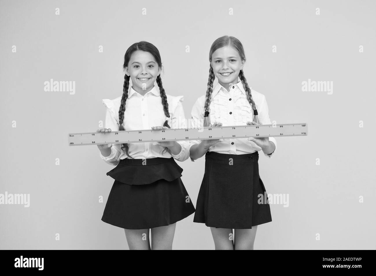 Measuring distance. Measuring equipment. Kids students study math. Knowledge day. Schoolgirls school uniform hold big ruler. Geometry school lesson. Teamwork concept. Close or far. Measuring skills. Stock Photo