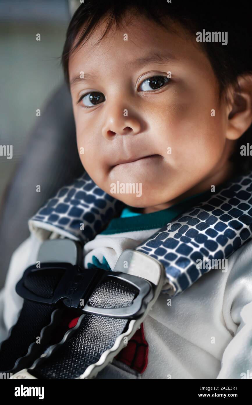 Handsome boy who is calm and happy while riding in a car and sitting in a convertible baby car seat with a secure seat belt harness. Stock Photo