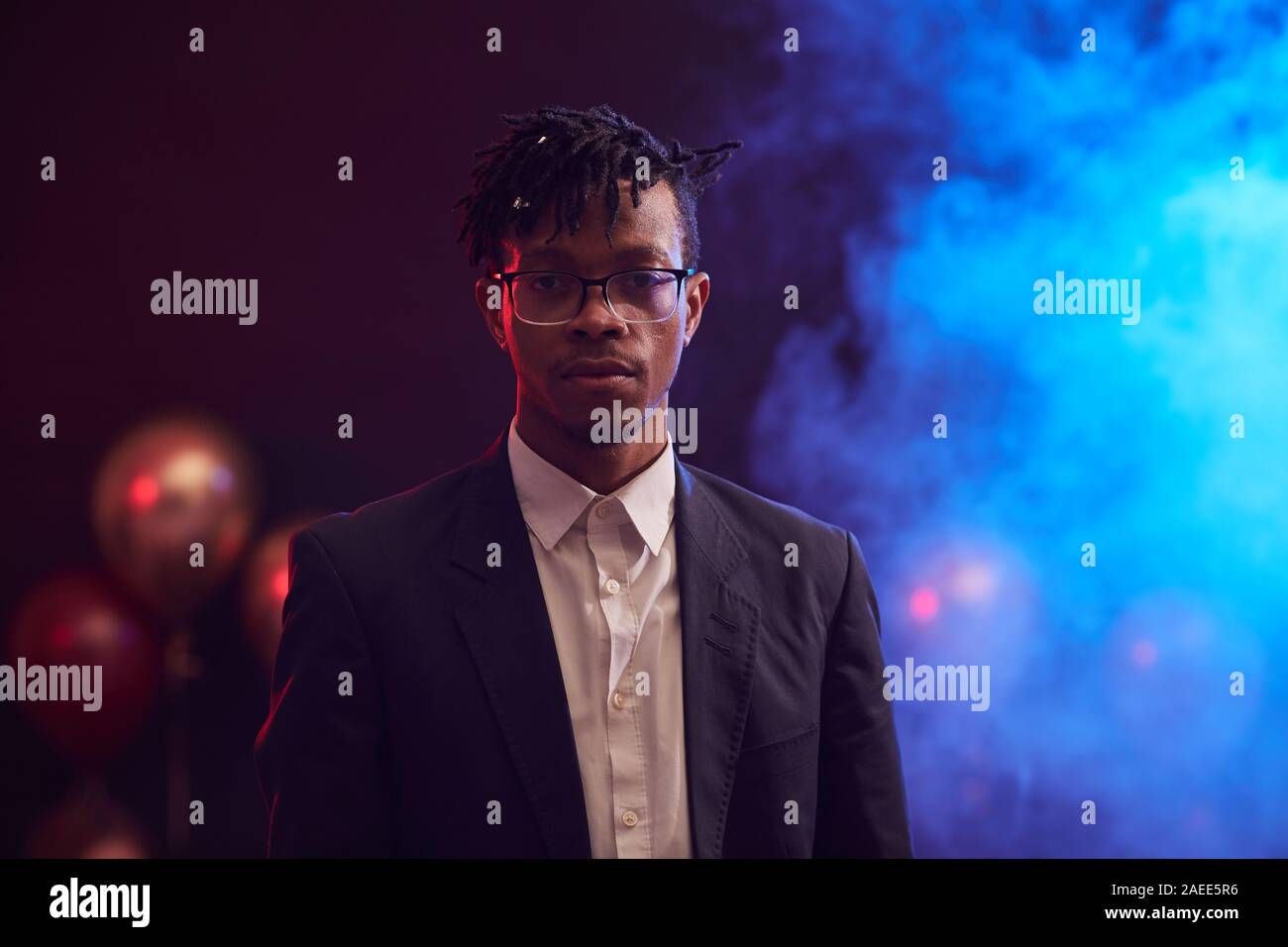 Waist up portrait of trendy African-American man looking at camera while standing in dimly lit room at nightclub, copy space Stock Photo