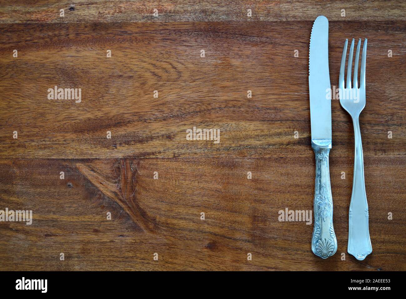 Background of a dark wooden table top, with an old fork and an old knife and plenty of space for text Stock Photo