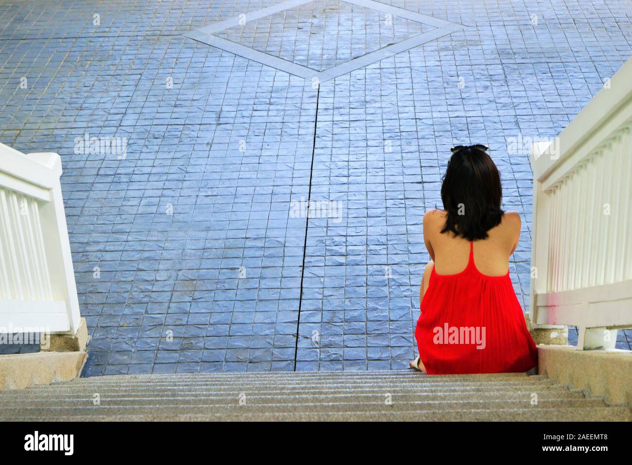 Women in red dress sitting on steps, Phuket, Thailand, Asia Stock Photo