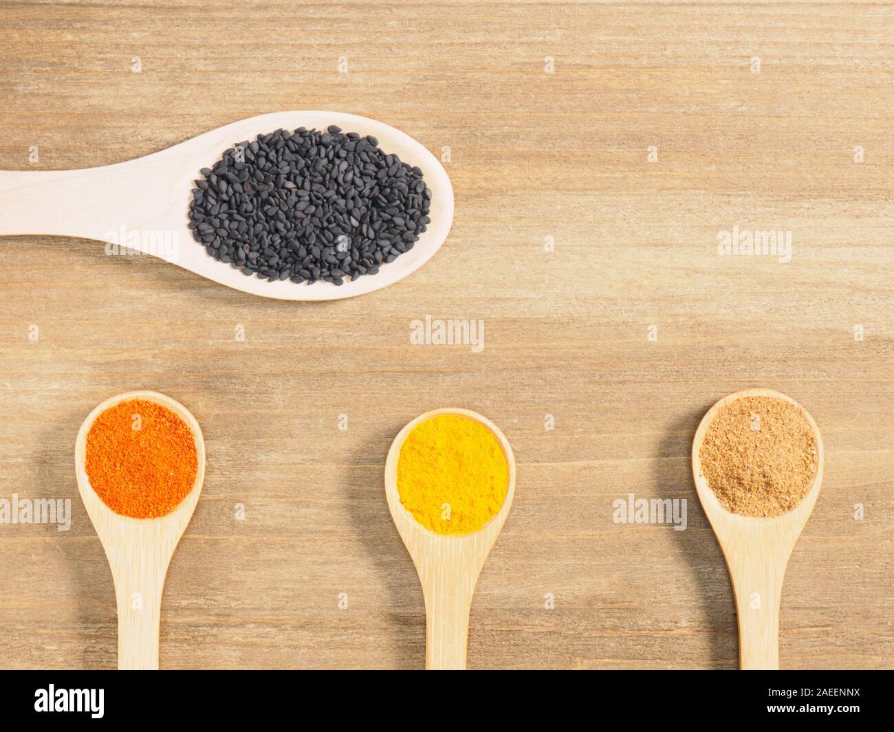 Turmeric, masala, chili pepper, black cumin in spoon on brown wooden