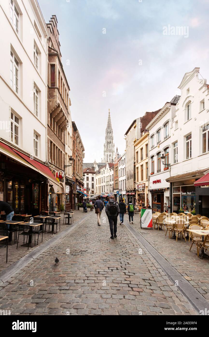 A street in Brussels with many restaurants and the Brussels Town Hall tower in the background, Belgium Stock Photo