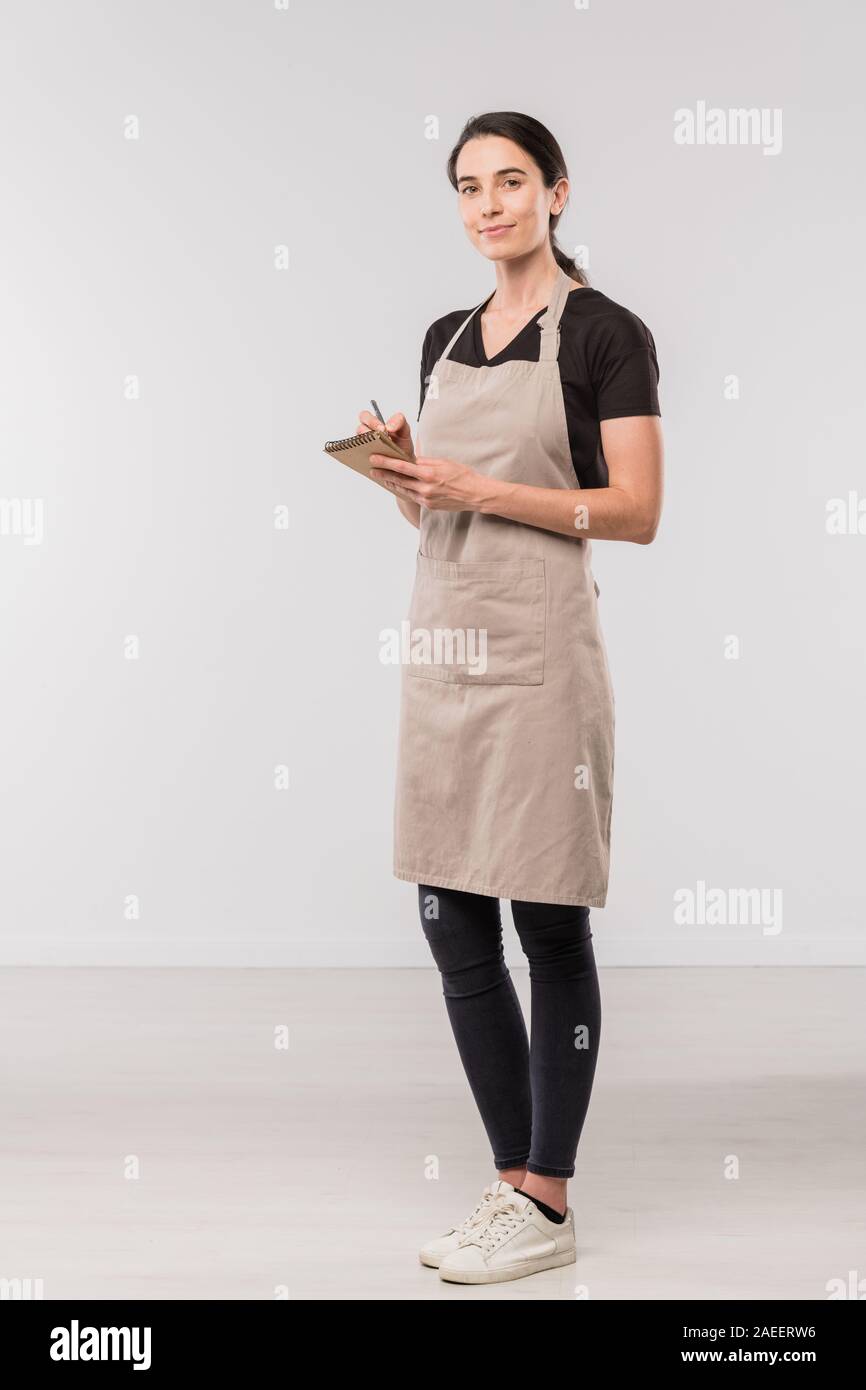 Pretty waitress in apron, black skinny jeans and tshirt making notes