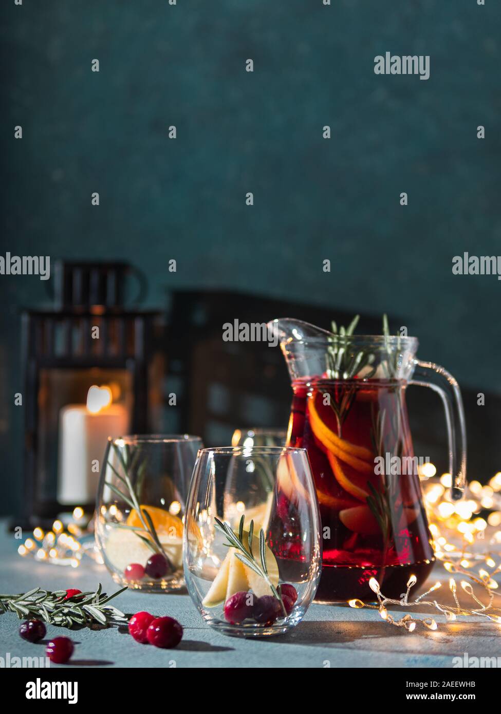 Winter sangria on dark christmas holiday background. Jugful of sangria and glasses with fruit slice, cranberry and rosemary. Copy space for text or design. Vertical. Stock Photo